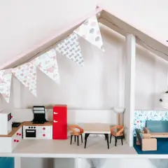Uroczy domek dla lalek DIY z kuchnią, jadalnią i salonem. Girlanda z makaroników dodaje mu uroku.