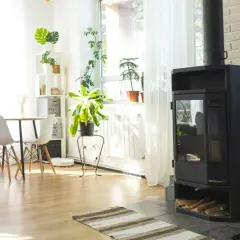Nowoczesny, wolnostojący kominek na pellet w jasnym salonie z jadalnią.