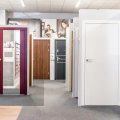 Salon okien i drzwi z ekspozycją drzwi, klamkami i materiałami informacyjnymi.