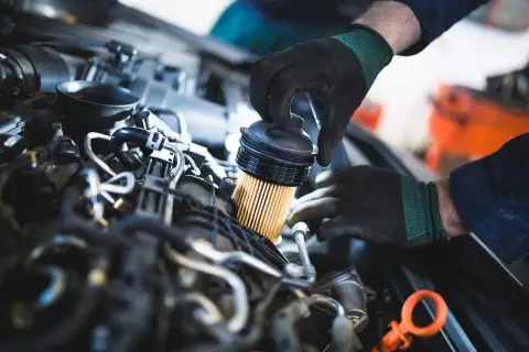 Mechanik wymienia filtr paliwa w silniku. To ważny element, który dba o czystość paliwa, podobnie jak filtr w pile spalinowej.