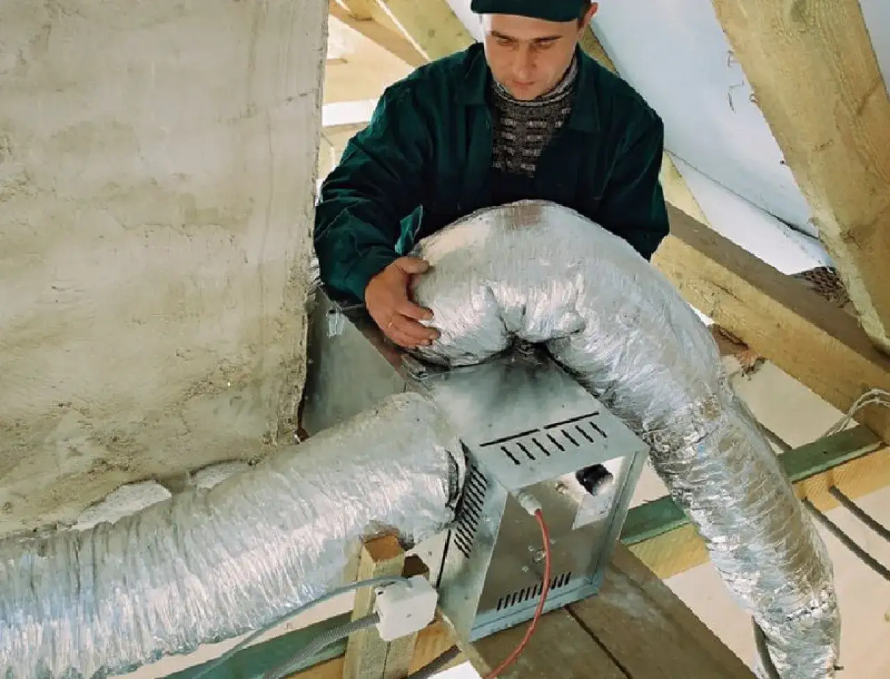Instalator montuje rury do rozprowadzenia ciepłego powietrza z kominka.